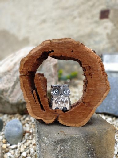 Dekoration Eine Eule aus Holz sitzt in einer hohlen Baumscheibe, welche indirekte Licht hat.